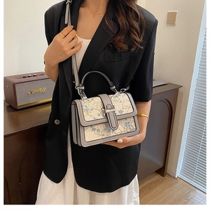 Elegant beige floral embroidery handbag with leather trim shown in a lifestyle setting