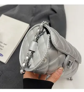 Gros plan du sac cylindrique argenté matelassé avec côté en métal poli et bandoulière