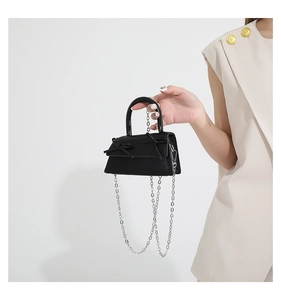 Close-up of black mini handbag with double bow decoration and silver metal chain strap