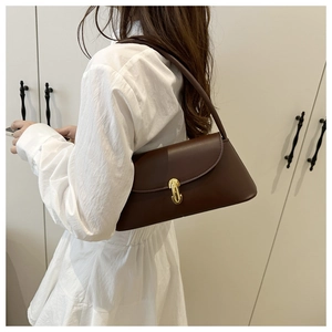 Detail view of a vintage dark brown leather underarm bag with gold metal buckle and strap