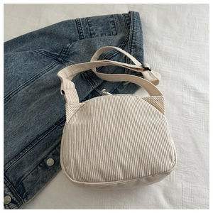 Détails de la sacoche en velours côtelé beige à côté d'une veste en jean bleue