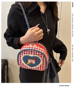 Detail of red and white plaid crossbody bag with denim heart patch and lace trim