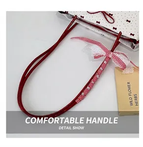 Detailed shot of red lacquer shoulder strap with bow decoration and white lace trim