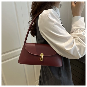 Close-up of vintage burgundy baguette bag with elegant golden metallic buckle closure
