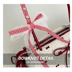 Detail of red bow ribbon and white lace trim on a cream polka dot bucket bag