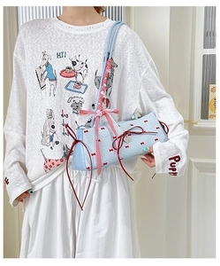 Detail of light blue bucket bag featuring red bow prints and decorative ribbons