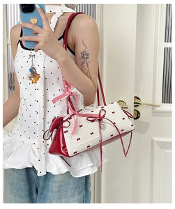 Detail of red and white polka dot bow shoulder bag with lace trim and heart charm