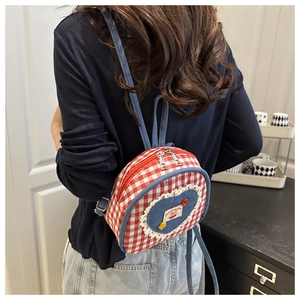Close-up of a mini red gingham backpack with heart denim patch worn by a model