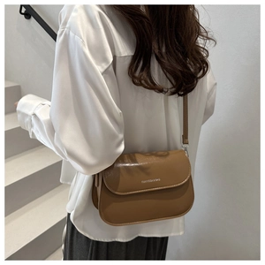 Close-up van een bruine kunstlederen crossbodytas met witte logobelettering op de trap