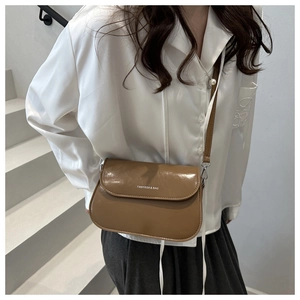 Detail van karamelbruine crossbodytas met wit logo op glad synthetisch leer