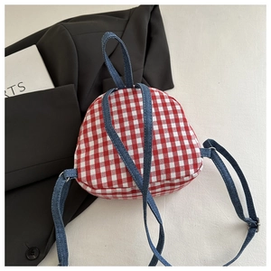 Detail of mini red and white checkered backpack with blue denim straps on black suit