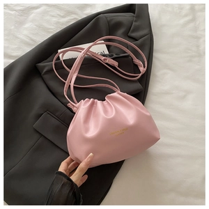 Close-up of the pleated pink leather bucket bag texture and golden logo detail