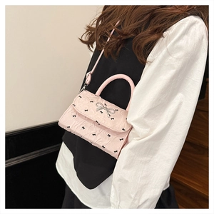 Détail du sac à main rose à nœud avec fermoir argenté sur une tenue élégante