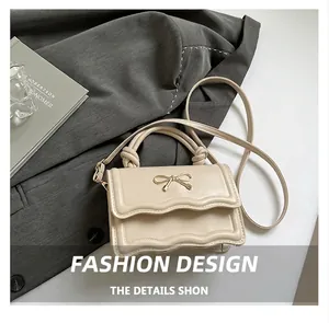 Detailed view of beige leather crossbody bag with bow hardware and scalloped flap