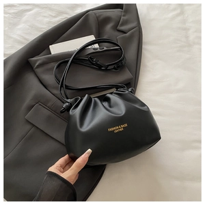 Detail of black pleated cloud bag with gold fashion lettering and adjustable strap