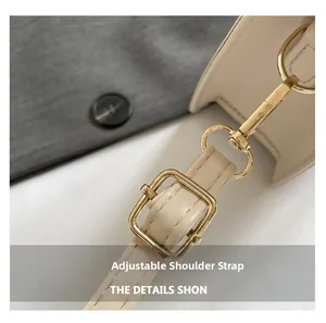 Detail of adjustable beige leather shoulder strap with textured gold metal buckle and hardware