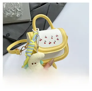 Detail of yellow girl's crossbody bag with cherry embroidery and plush moon pendant