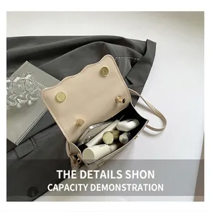 Detail of spacious beige shoulder bag interior showing phone, earbuds and cosmetics