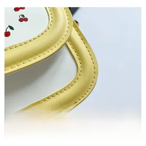 Detail of sweet cherry print on yellow and white PU leather with neat stitching