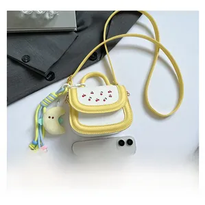 Detailed size comparison of a yellow mini crossbody bag with a smartphone and cherry detail