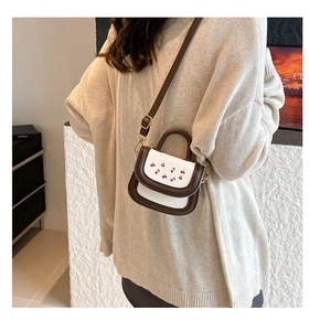 Mini crossbody bag featuring cherry print with adjustable strap worn by model