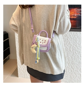 Mini purple handbag with cherry print and yellow moon pendant on a beige sweater