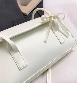 Détail du sac baguette en cuir PU blanc avec poignée tressée et décoration de nœud élégant