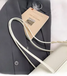 Gros plan d'un sac à main blanc élégant avec de fines anses posé sur une veste grise