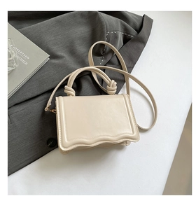 Detail showing wavy bottom edge and knotted handle design on beige chic handbag
