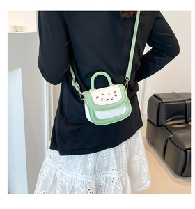 Detailed shot of a mint green and white mini bag featuring red cherry embroidery on back
