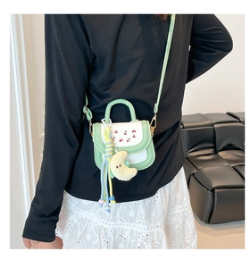 Close-up of mint green girls purse with cherry print, moon plushie and colorful bead charms