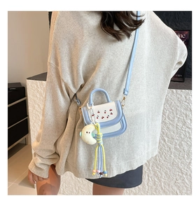 Detail of a mini cherry print crossbody bag showing size and fit on a child model