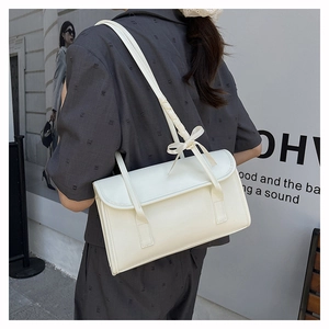 Detail of cream white leather baguette bag featuring elegant side bow shoulder strap