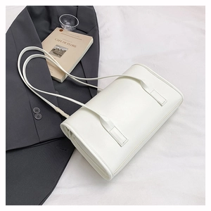 Flat lay of a white leather shoulder bag styled with a blazer and lifestyle props