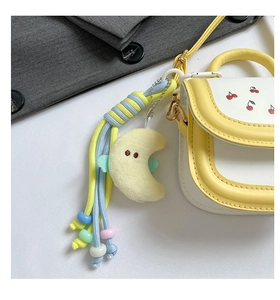 Close-up of yellow and white leather handbag with cherry embroidery and moon charm