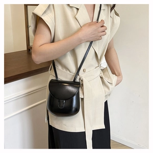 Model wearing a black matte saddle crossbody bag with a slim strap for a stylish look