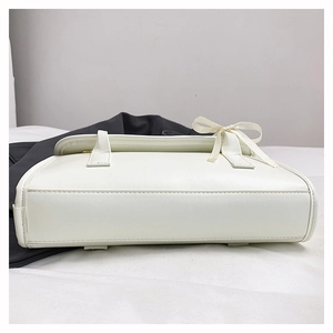 Detailed bottom view of white leather shoulder bag with a satin bow and fine stitching