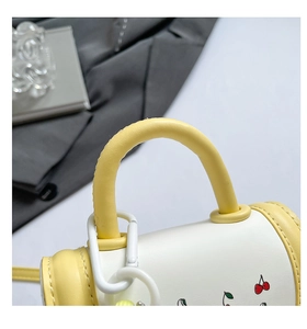 Close-up of yellow PU leather handle with cherry print and metallic hardware detail