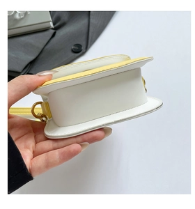 Detailed view of the yellow and white small handbag showing the metal D-ring and stitching