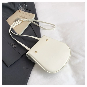 Macro shot of white saddle bag with gold metal studs on gray blazer background