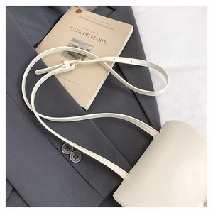 Detailed close-up of a minimalist cream white crossbody bag with smooth faux leather texture