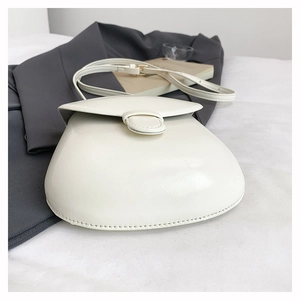 Detailed view of the smooth white leather semi-circular crossbody bag with fine edge stitching