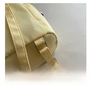 Detail of the silver metal ring connection on a light yellow fabric casual backpack