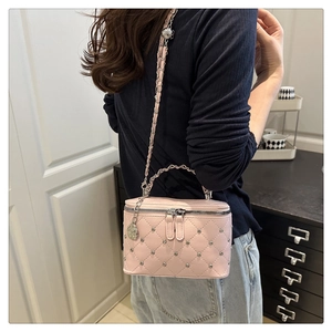 Pink quilted box bag with silver studs and chain strap shown on model outdoors