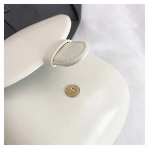 Detailed macro shot of a white saddle bag featuring a gold magnetic snap and fine stitching