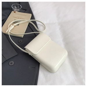 Detail of minimalist cream leather crossbody phone bag with fine stitching on grey blazer