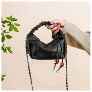 Détail du sac à main plissé noir avec cordon en perles d'ambre et cuir texturé