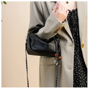 Détail du sac à chaîne noir avec perles d'ambre et surface en cuir texturé