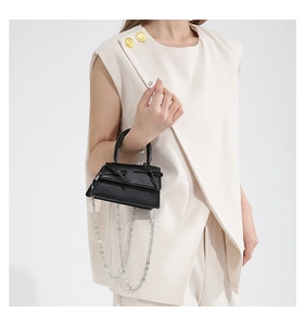 Detail of black mini trapezoid handbag with bow decoration and silver metal chain strap