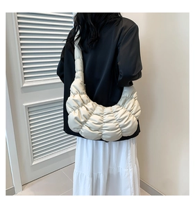 Detail of beige pleated hobo bag showing soft quilted texture and wide shoulder strap